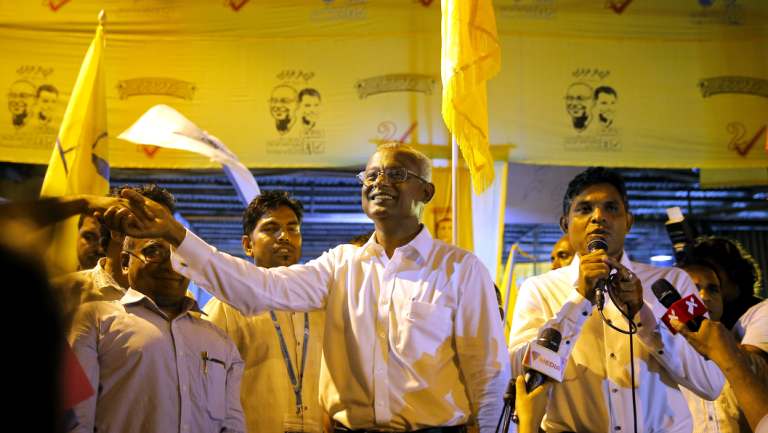 Maldives' opposition presidential candidate Ibrahim Mohamed Solih, centre, shakes hands with a supporter as his running mate, Faisal Naseem, right, addresses the gathering in Male, Maldives, on Monday.