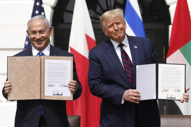 Israel's Prime Minister Benjamin Netanyahu and US President Donald Trump hold signed documents relating to the Middle East deal. 