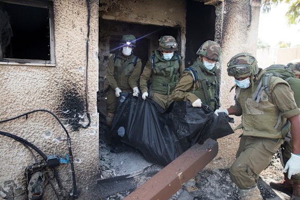 Israeli soldiers remove the body of a person who was killed days earlier in an attack on the Kfar Aza kibbutz.