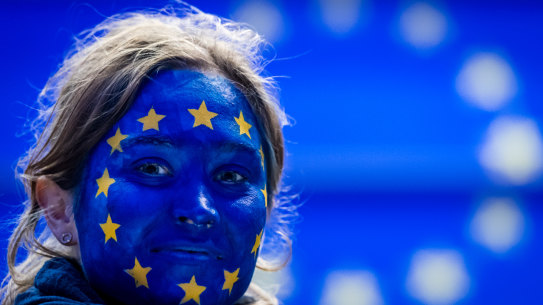 A woman wearing face paint in a European Union flag design follows the results of the European Parliament elections in Brussels.