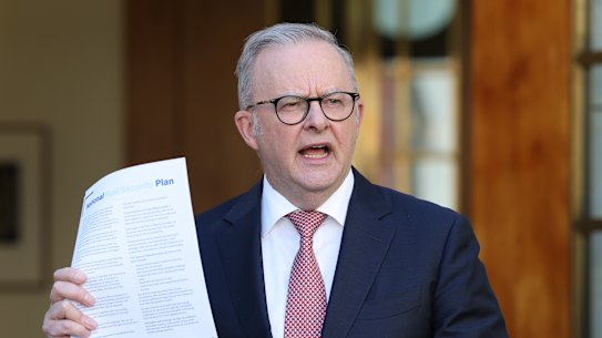 Prime Minister Anthony Albanese holds a copy of the national fuel plan at a press conference on Monday.