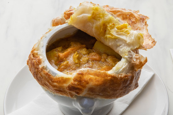 Peel back the lid of the chicken curry pot pie to uncover big chunks of chook and vegetables.