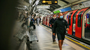Commuters in masks walk along a platform at Bank station on the London Underground. 