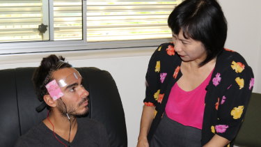 Professor Colleen Loo applies a transcranial direct-current stimulation device to an unnamed volunteer.
