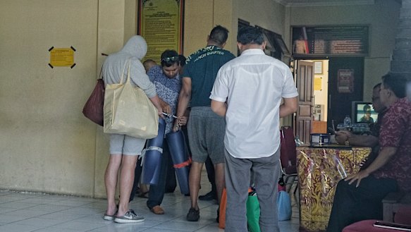 Australian nightclub promoters William Cabantog (blue shirt) and David Van Iersel (grey shirt) are transferred between cells at Denpasar police station.
