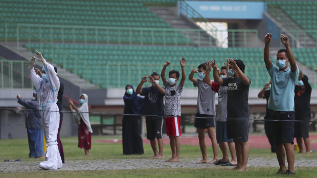A health worker wearing protective suit performs exercise with patients at the Patriot Candrabhaga stadium outside Jakarta. The stadium was turned into an isolation centre for people showing symptoms of COVID-19.