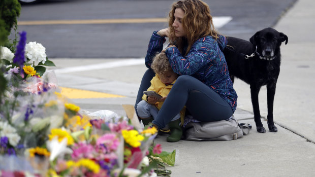 Ali De Leon and her son pause at a growing memorial across the street from the Chabad of Poway synagogue.