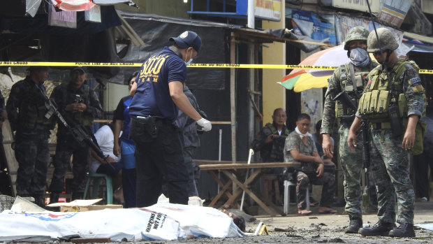 Police investigators examine the site after the January bombings in Jolo, Philippines.