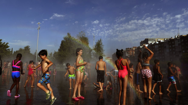 Children cool off in an urban beach at Madrid Rio park in Madrid.