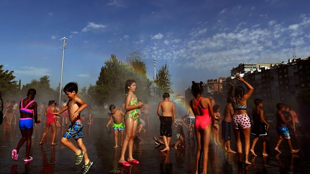 Children cool off in an urban beach at Madrid Rio park in Madrid.