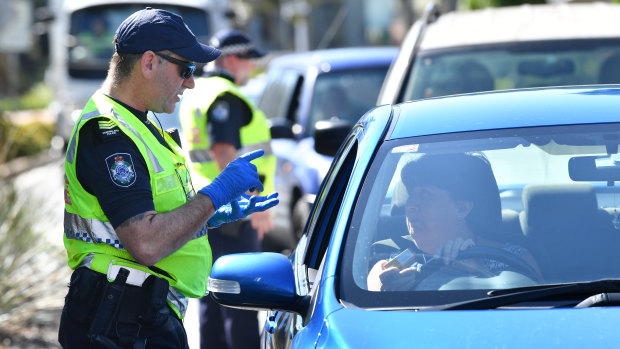 Police stop cars at a checkpoint on the Queensland and New South Wales border on Friday.