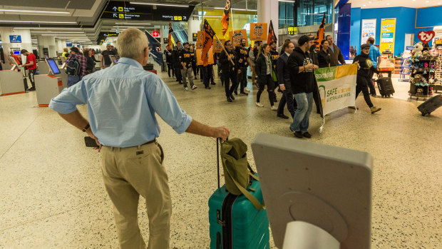 A passenger watches Jetstar workers and union officials at Melbourne Airport.