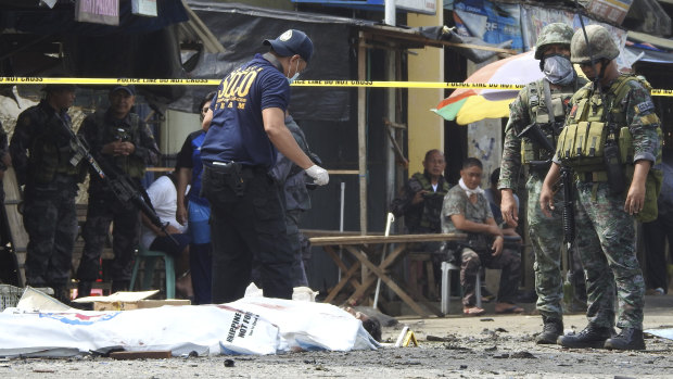 Police investigators examine the site after the bombings in Jolo, Philippines.
