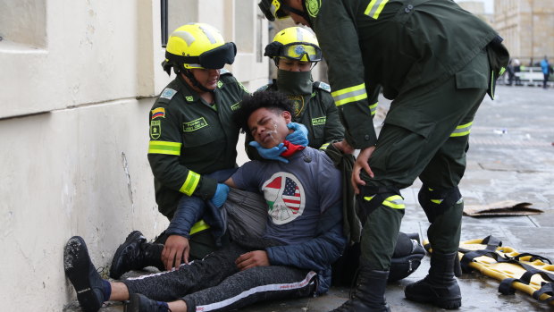 Police attend to an anti-government protester affected by tear gas during clashes in downtown Bogota, Colombia.