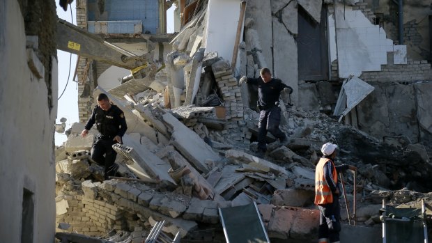 Rescuers search a damaged building after a magnitude 6.4 earthquake in Thumane, western Albania.