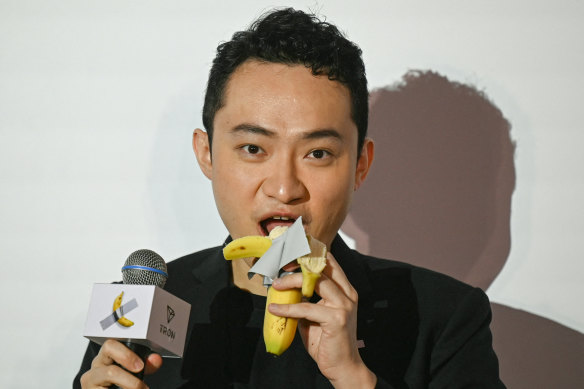 Chinese-born crypto founder Justin Sun eats the organic part of a banana artwork composed of a fresh banana stuck to a wall with duct tape, in Hong Kong.