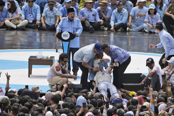 A supporter who passed out due to the heat is helped to safety as Prabowo Subianto speaks.