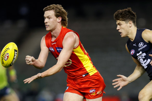 Noah Anderson handpasses as Carlton’s Liam Stocker closes in.