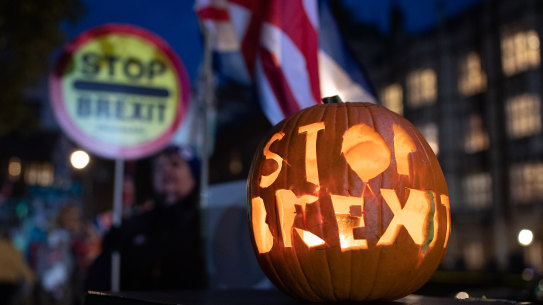 Anti-Brexit activists stand with a "Stop Brexit" halloween pumpkin outside the Houses of Parliament on October 29.