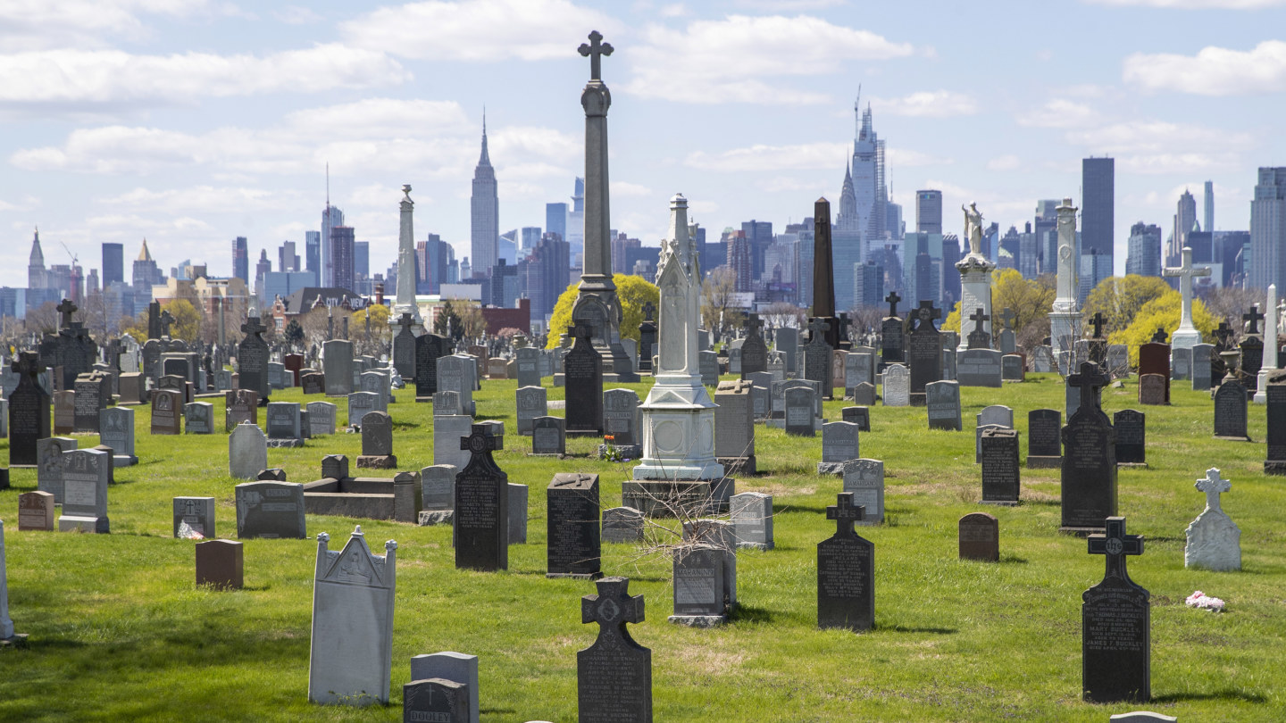 The Empire State building and the Manhattan skyline are seen behind the tombstones at Calvary Cemetery, Saturday, April 11, 2020, in the Maspeth neighborhood of the Queens borough of New York. The U.S. has recorded nearly 20,000 deaths from the coronavirus, overtaking Italy for the highest death toll in the world. Nearly half of the deaths in the United States happened in the New York state, but fear is mounting over the spread of the virus into the nation's heartland.
