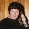 The premier-elect of Victoria Joan Kirner on August 9, 1990. Kirner was the first female premier of Victoria. In this photograph Kirner is on the phone and surrounded by congratulatory flowers.