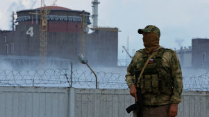A serviceman with a Russian flag on his uniform stands guard near the Ukrainian Zaporizhzhia Nuclear Power Plant now controlled by Moscow.