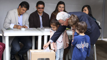 Former Colombian president Alvaro Uribe casts his ballot, accompanied by his grandchildren on Sunday.