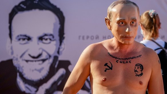 A man wearing a Vladimir Putin mask takes part in a demonstration for prisoned Alexei Navalny, poster at left, in Geneva, Switzerland.