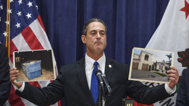 Orange County District Attorney Todd Spitzer holds up pictures of the home of Peter Chadwick and the dumpster where his wife's body was found.