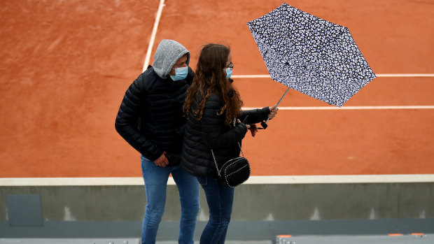 Fans head for shelter as rain falls during day one of the 2020 French Open at Roland Garros.