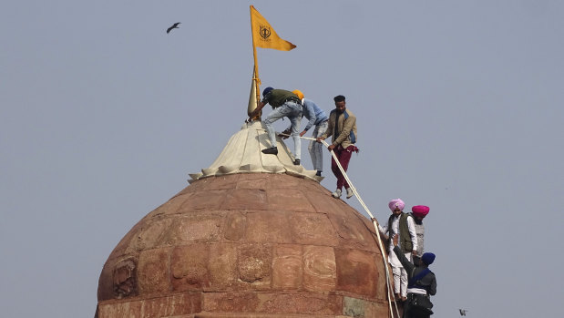 Sikhs hoist a Nishan Sahib, a Sikh religious flag, on a minaret of the historic Red Fort monument in New Delhi, amid protests by farmers.