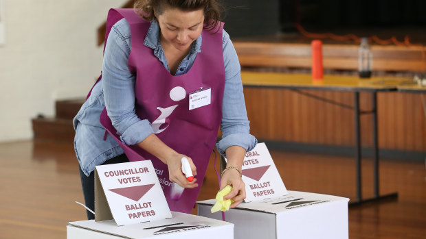 An election official sanitises the ballot boxes.