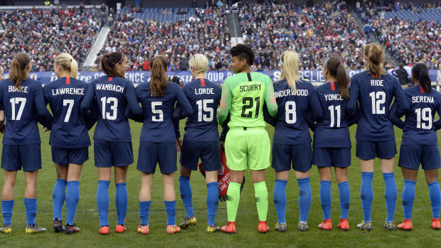The US women's soccer team stands arm in arm, wearing jerseys with the names of women have inspired each player.
