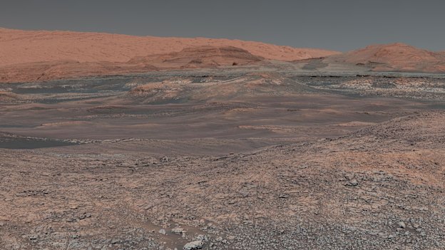 Welcome to Mars, where Mount Sharp rises in the distance. In the middle ground are clay-bearing rocks that scientists hope will help ascertain the role of water on the planet.