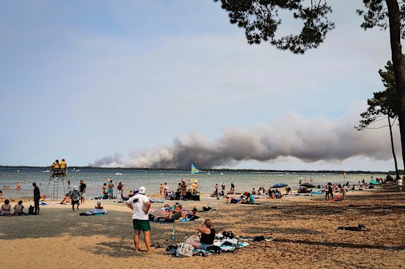 People on the beach in Biscarrosse, south-western France as a cloud of smoke rises from a fire raging in the northern part of the Arcachon Basin.
