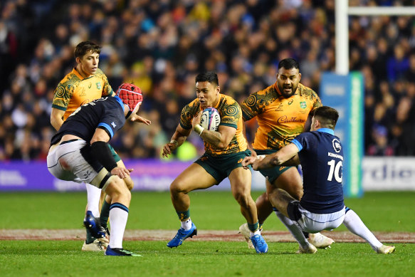 Len Ikitau of Australia is challenged by Grant Gilchrist and Blair Kinghorn of Scotland.