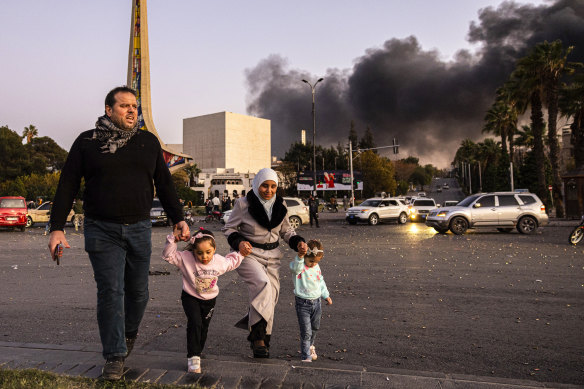 Smoke billows as people arrive in Damascus to celebrate the fall of the Syrian government.