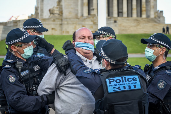 Police put a mask on a protester at the Shrine on Saturday.