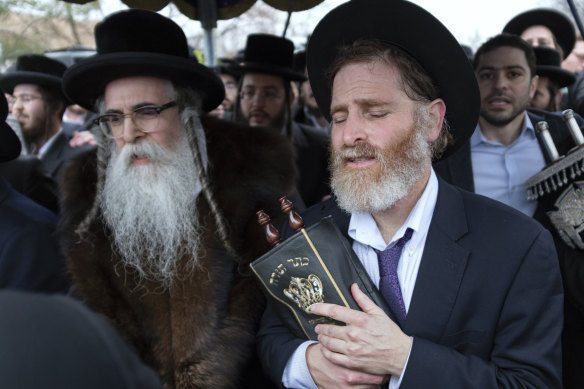 Community members, including Rabbi Chaim Rottenberg (left), celebrate the arrival of a new Torah near the rabbi's residence in Monsey, New York, a day after the knife attack.