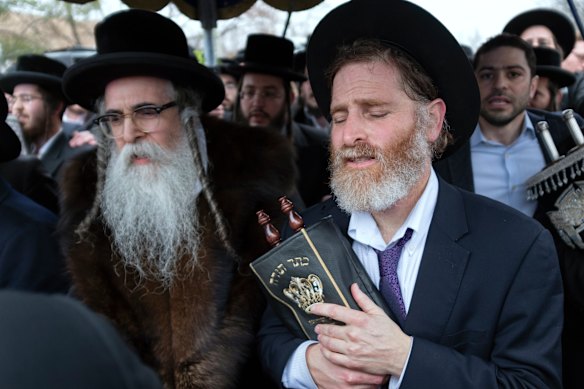 Community members, including Rabbi Chaim Rottenberg (left), celebrate the arrival of a new Torah near the rabbi's residence in Monsey, New York, a day after the knife attack.