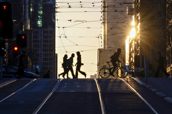 City workers crossing La Trobe Street as the sun rises on a warm winter Monday.
