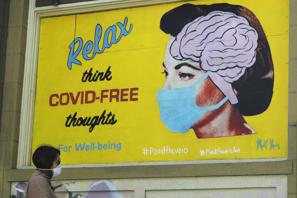 A woman wears a face mask while walking under a sign that reads "Relax think COVID free thoughts" during the coronavirus outbreak in San Francisco. 