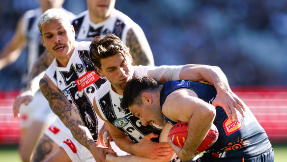Chayce Jones of the Crows is tackled by Patrick Lipinski of the Magpies.