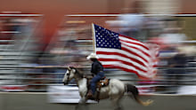 A horse rider carrying the American flag at a rodeo in the USA.