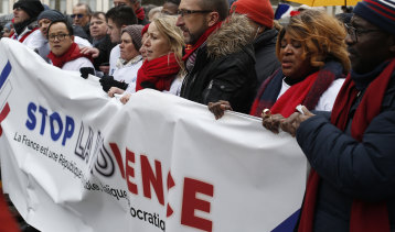 Protesters carry an anti-violence banner through the streets of Paris on Sunday.