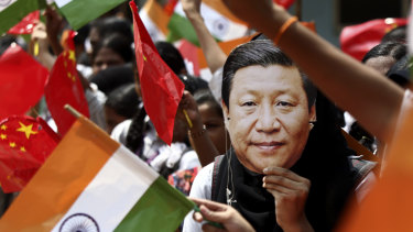 An Indian schoolgirl wears a mask of Chinese President Xi Jinping to welcome him last year. 