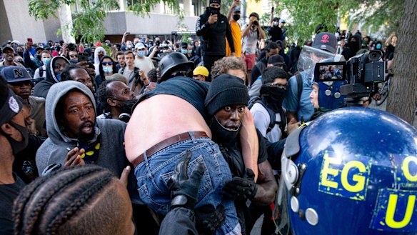 A group of men carry an injured man away after he was allegedly attacked by some of the crowd of protesters as police try to intervene on the Southbank near Waterloo station.