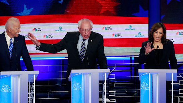 Democratic presidential candidate Senator Bernie Sanders, centre, gestures towards former vice-president Joe Biden as Kamala Harris talks.