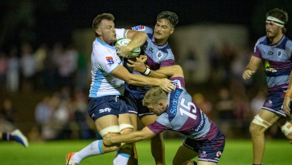 Waratahs back-rower Jack Dempsey is tackled by Reds backs Jordan Petaia and Bryce Hegarty. 