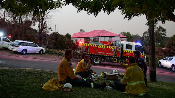 Firefighters take a break near properties where fire retardant was dropped on Barwon Avenue during a fire in South Turramurra.